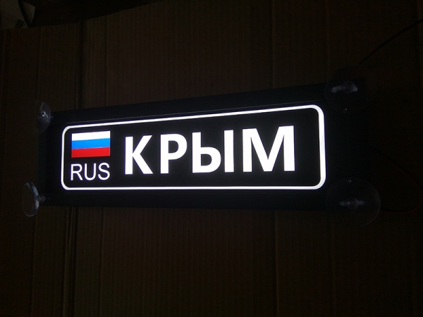 Именная светящаяся табличка на стекло Крым RUS Табличка Крым RUS  на стекло. Светящаяся табличка в стиле госномера с цифрами региона. Светящаяся табличка с именем водителя на стекло автомобиля, крепление на присоски, изготовление на заказ.